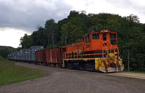 A red and yellow train on train tracks with trees behind it