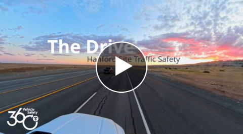 A view from on top of a car driving into a pink and blue sunset. The photo has a play button in the middle of it