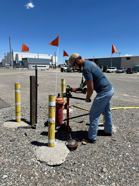 A man works on a pump coming out from the ground outside