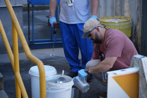 Workers prepare grout in containers.