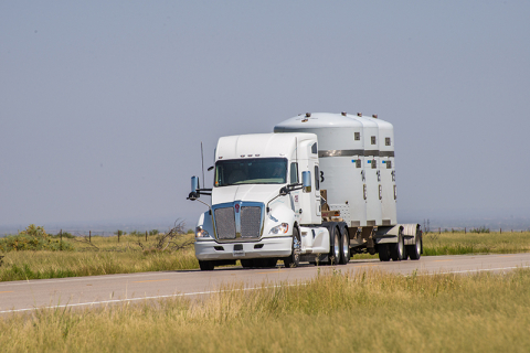 A white eighteen wheeler truck driving on an open road