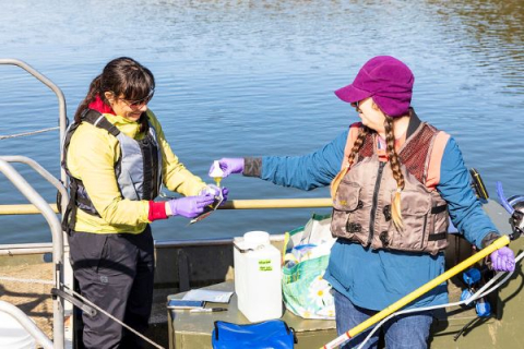 ORNL staff collecting water samples on boat in a lake
