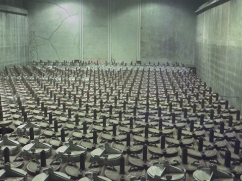 A large room with concrete walls full of black containers