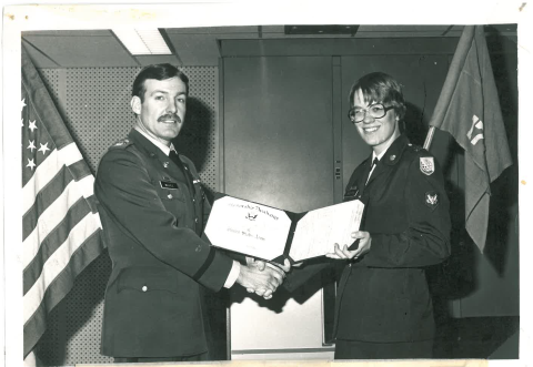 Two people in military uniforms. One receiving an award. 