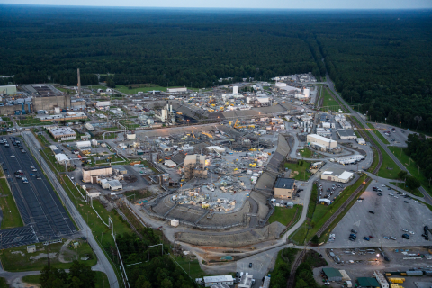 An aerial shot of a tank farm with lots of buildings and tanks surrounded by trees