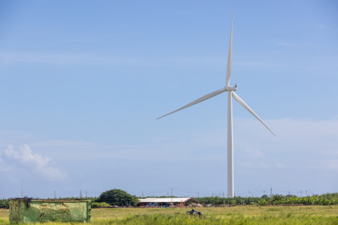 Wind Turbine on a farm next to a red building. 