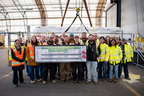 A large group photo, the front row holds up a white banner