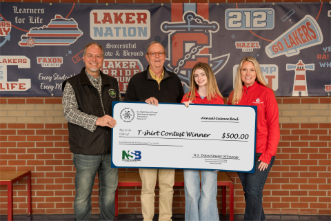 Four people pose for a picture while holding a large check for $500