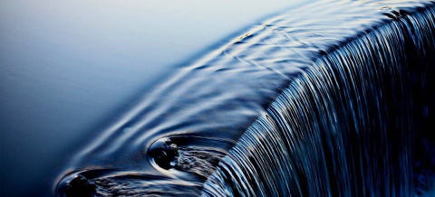 Closeup dark water flowing over waterfall