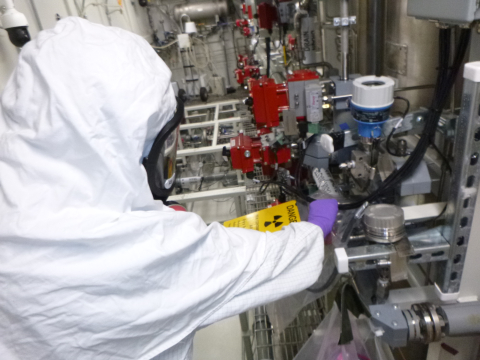 An employee in a white hazmat suit  performs maintenance works inside a facility building