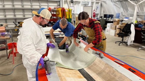 Workers filling a wind turbine blade mould in a lab
