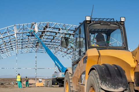 A yellow construction vehicle working to pull down an enclosure 