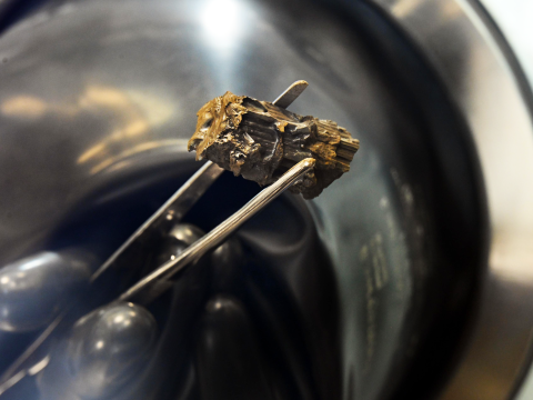 silver tweezers holding gray fuel salt
