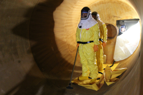 Employees standing on the inside of large surge drums performing work