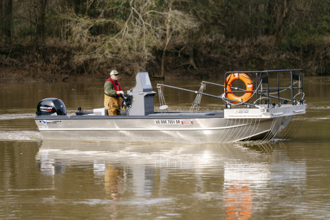 A man wearing a lifejacket inside a fishing boat on the water