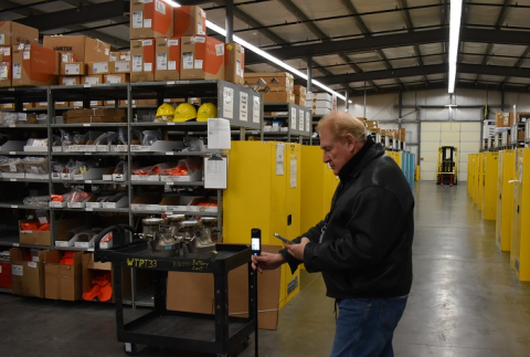 A man sets up a special 360-degree camera inside a plant warehouse.
