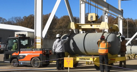 Employees using a tow motor to move a large cylinder