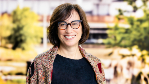 Lois Curfman McInnes (a white woman in a black t-shirt and multicolored printed shirt over it) outside
