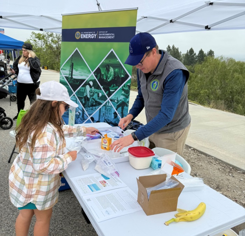 Employee at a street fair booth talking to a child