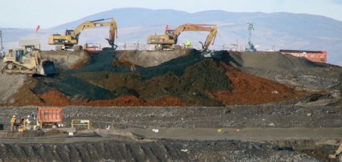 Excavators working on top of a hill with hills in the background.