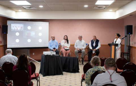 A panel of speakers sit on stage for a community forum event