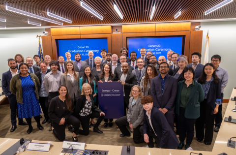 A group of 41 people in business attire pose and smile for the camera in a meeting room.