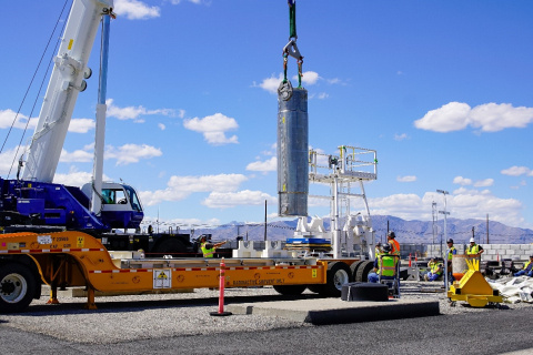 A crane lifting a large, metal, cylindrical object