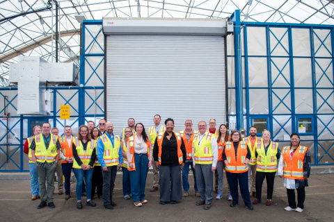 A group of individuals posing for a group picture outside of a facility building