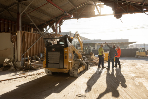 Employees working inside a demolished building with construction vehicles