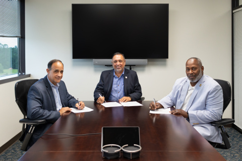 Three professionals sitting at a conference table posing for a group photo