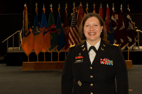 A woman in a uniform posing for a picture in front of flags