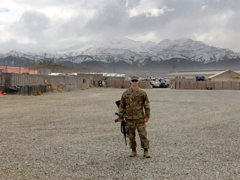 A man in a Military uniform posing for a picture outside