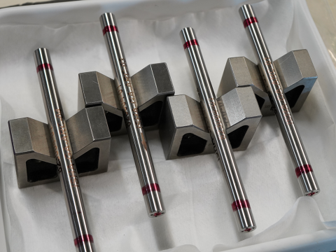Four silver metallic fuel rod samples on display