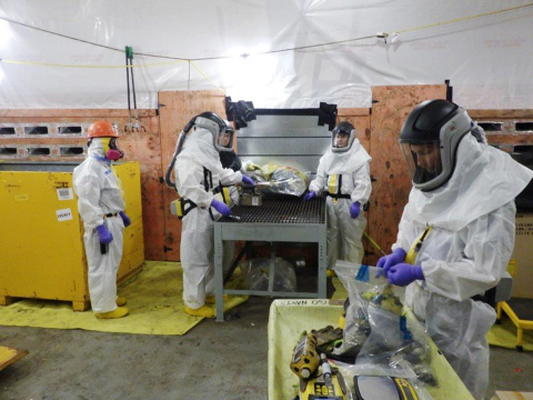 Sanitation workers in white safety gear working