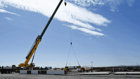 A rotating set of images of large cranes lifting and placing materials at the Hanford Site