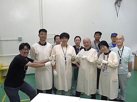 A man points to a group of nine people with an excited expression on his face and points to the group.