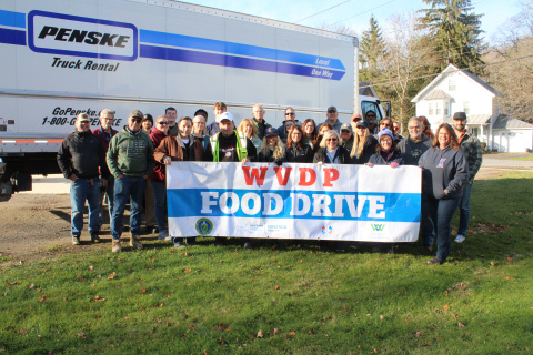 A group of people holding a food drive sign posing for a picture