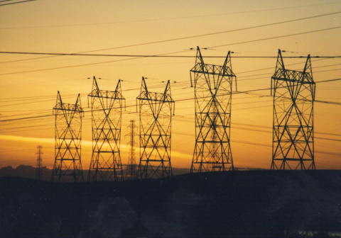 A row of power lines on the horizon, with the sky beyond in the midst of a setting sun.