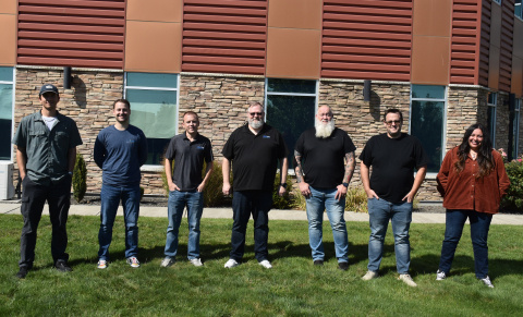A group of people pose for a photo outside of an office building