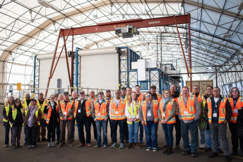 A large group of people in orange safety vests posing for a photo at the Los Alamos site
