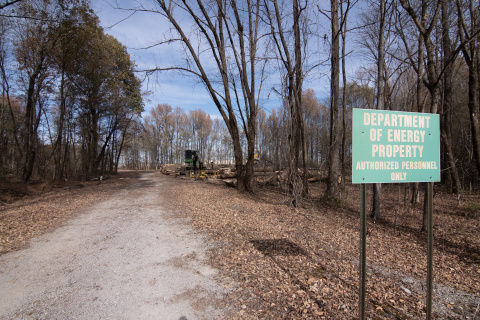 A road lined with trees with a green sign that reads "Department of Energy Property"