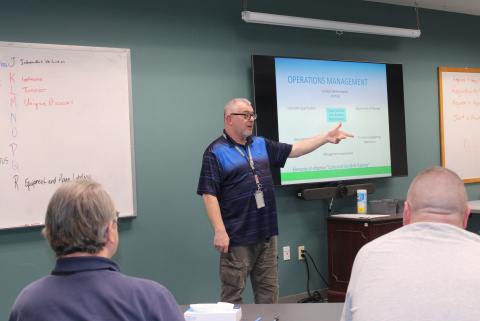 A man at the front of a classroom giving a presentation