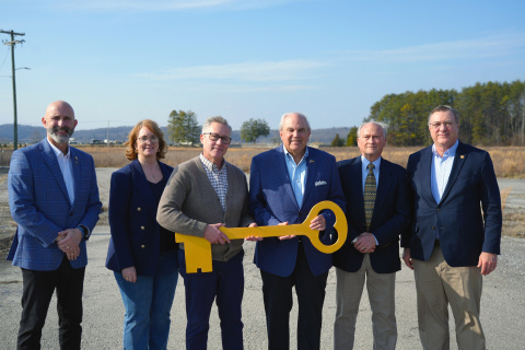 Four men and one women post with a large gold key outside on the site