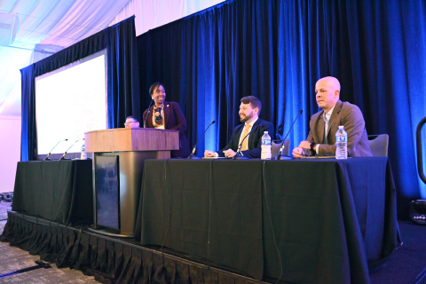 A group of professionals participating in a panel on stage at a conference