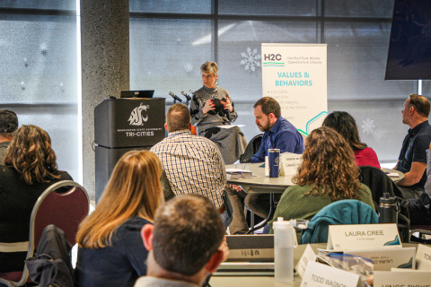 A woman on stage sitting in a chair speaking to a crowd