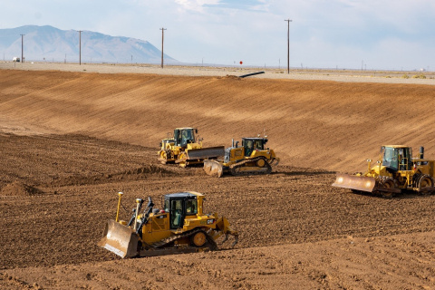 Four yellow construction vehicles within a large dirt filled disposal facility at the Idaho site