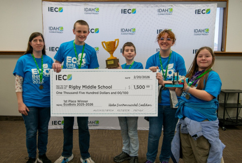 A group of student holding a trophy and a large check after winning a competition