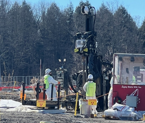 Employees in protective gear standing beside a groundwater sampling machine