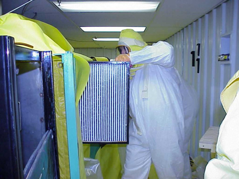 An employee in protective gear removing a filter at the West Valley site