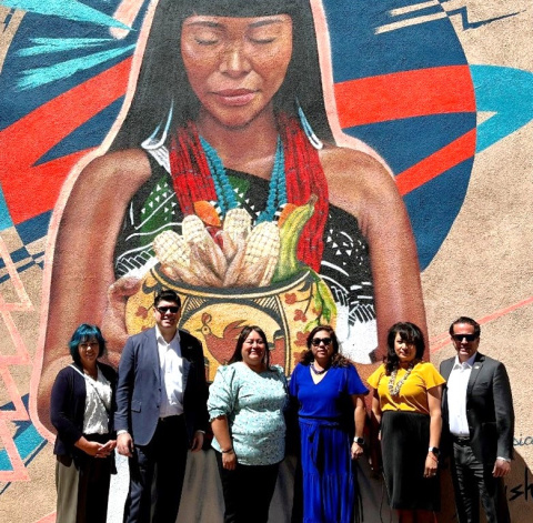 A group of people posing for a picture in front of a mural